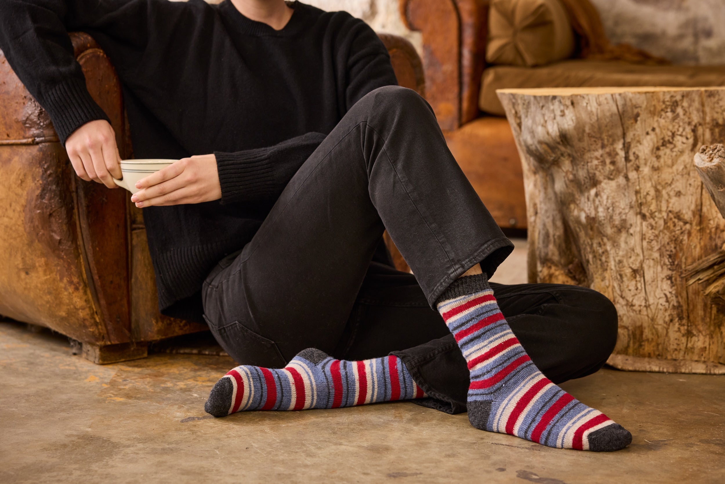 Woman wearing striped socks sitting on a couch with a rustic background